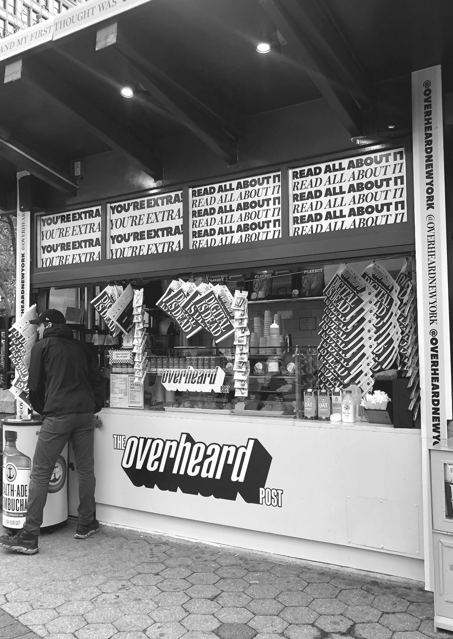 A reader at a street newsstand branded The Overheard Post
