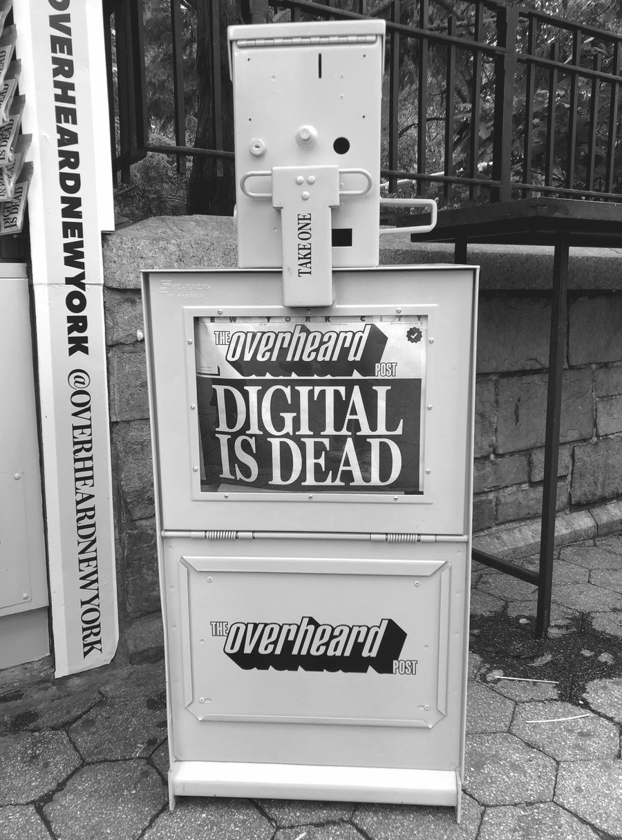 An Overheard Post newspaper vending box on a city sidewalk